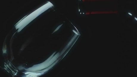 Leaning glass on a black background filled with red wine