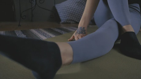Legs of a woman doing stretching on the floor.