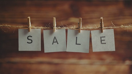 Letters spelling the word sale hanging on a rope.