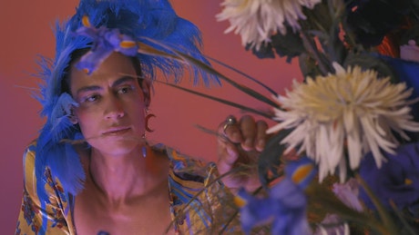 LGBTQ boy with extravagant clothes, with feathers and flowers.
