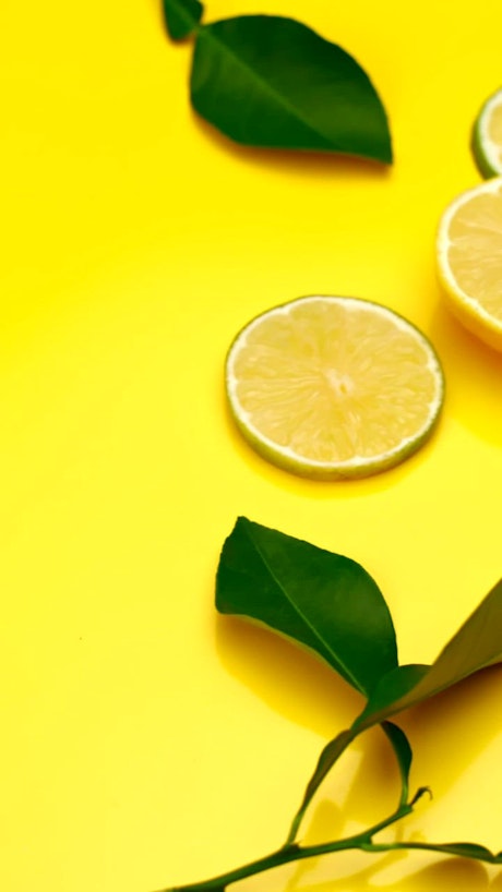 Lime and orange slices are beautifully arranged over a yellow background.
