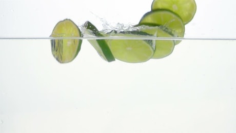 Lime slices falling through water.