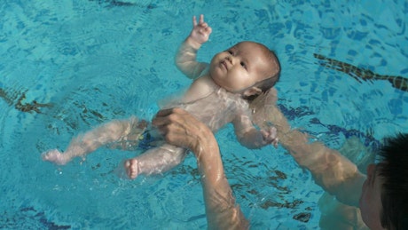 Little baby learning to float in the pool water.