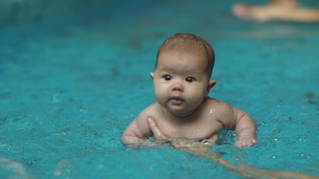 Little baby learning to swim in a pool.