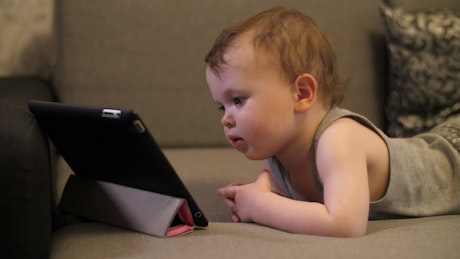 Little baby looking to a video on a tablet.