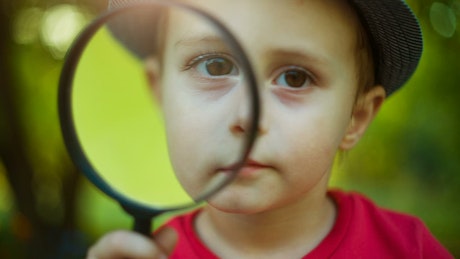 Little boy looking through a magnifying glass