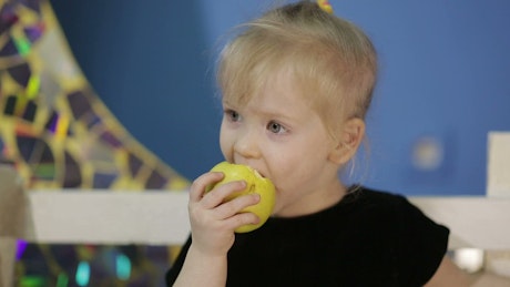 Little girl eating an apple.