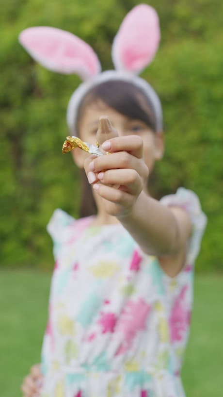 Little girl eating easter egg chocolate in the garden.