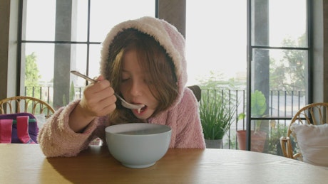 Little girl having breakfast while her dad