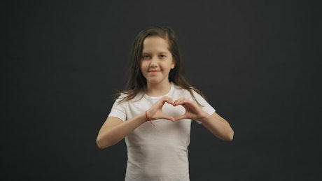 Little girl making sweet heart hands sign.