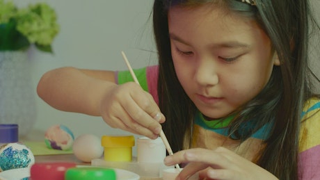 Little girl painting easter eggs.