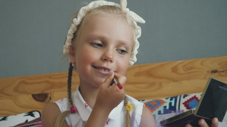 Little girl painting her lips.