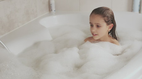 Little girl plays with the foam from her tub.