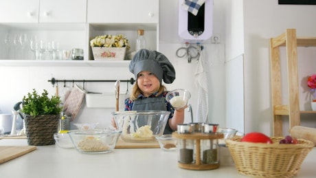 Little girl preparing a mixture in a kitchen.