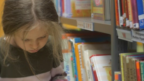 Little girl reading a book in a library
