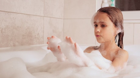 Little girl taking a bath in the tub
