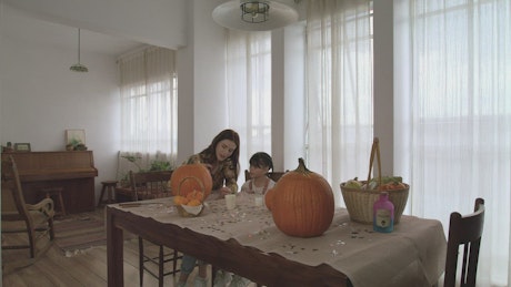 Little girl with her mother making decorations for halloween.