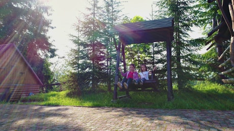 Little girls on a swing in the country house.