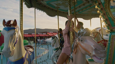 Little kids enjoy the carousel fair attraction in the sunset.