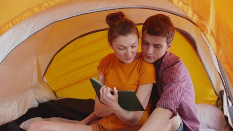 Loving couple reading a book together in a tent.