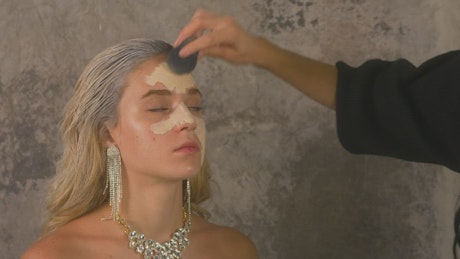 Makeup artist applying base to a model's face.