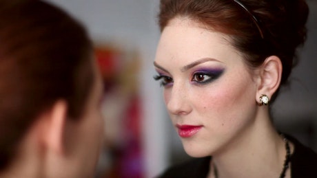 Makeup artist doing makeup on a young woman.