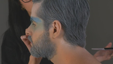 Makeup artist painting a man's face in winter concept.