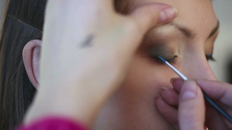 Makeup brush painting a woman eye.