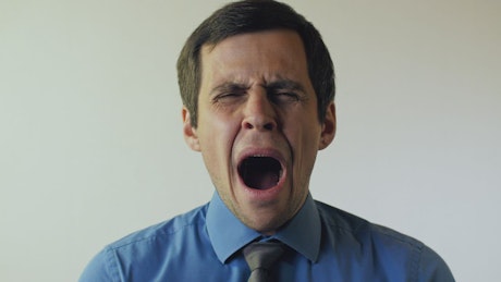 Male office worker yawning, portrait.