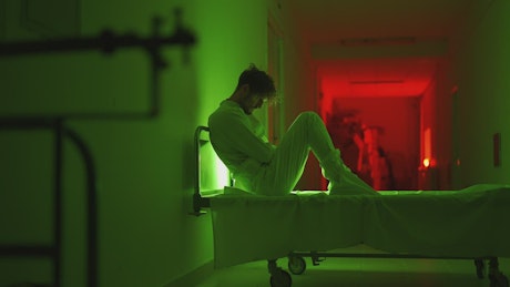 Male patient sitting on a gurney in a creepy hospital.