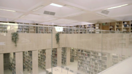 Male student in library reading next to stacks of books.
