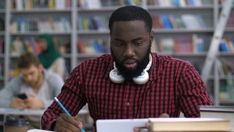 Male student reading in the library.
