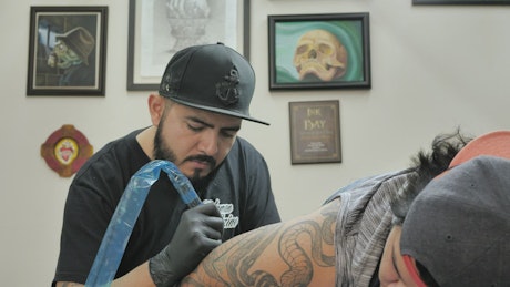 Male tattooist working on a tattoo.