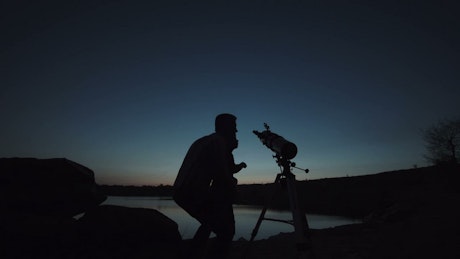 Man and a boy you using the telescope at dusk