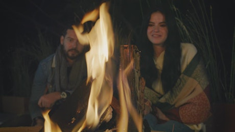 Man and woman burning marshmallows on a campfire.