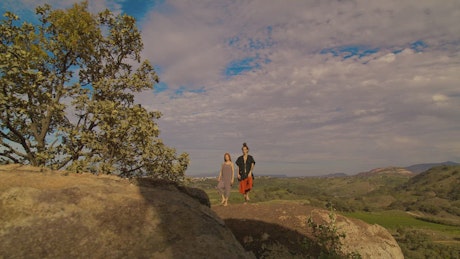 Man and woman meditating on a big rock in nature.