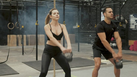 Man and woman using Russian kettlebell