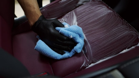 Man carefully cleaning a leather interior of a car.