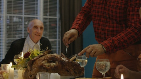 Man carving turkey on Thanksgiving dinner.