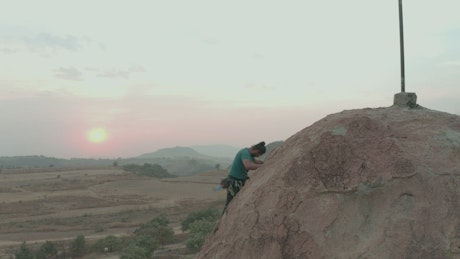 Man climbing to the top of a large rock.