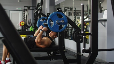 Man completing a bench press at the gym.