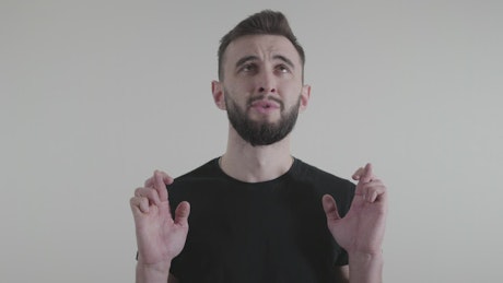 Man crossing fingers in front of a white background.