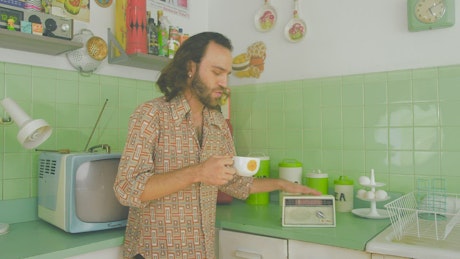 Man dancing while drinking coffee in an 60s kitchen.