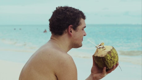 Man drinking from a coconut.