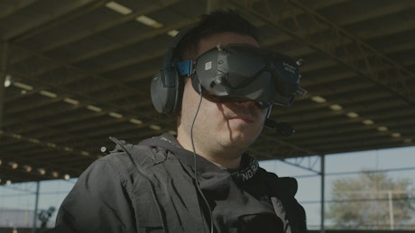 Man flying a drone with a controller and VR glasses.