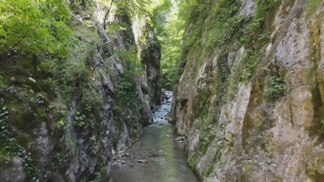 Man hiking in a canyon with a stream.