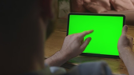一名男子拿着一块空白绿色屏幕的平板电脑