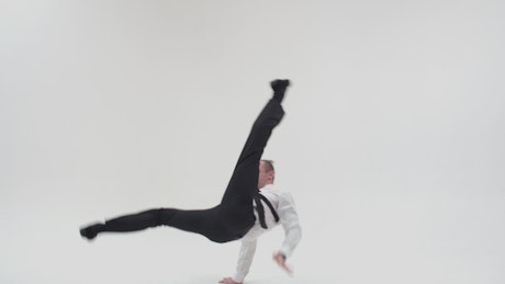 Man in a suit breakdances against a white background.