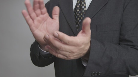 Man in a suit clapping, close up.