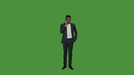 Man in a suit on the phone on a green screen.